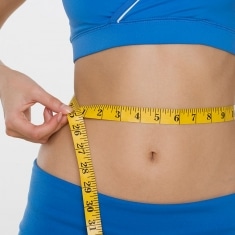 woman measuring her waist with a tape measure