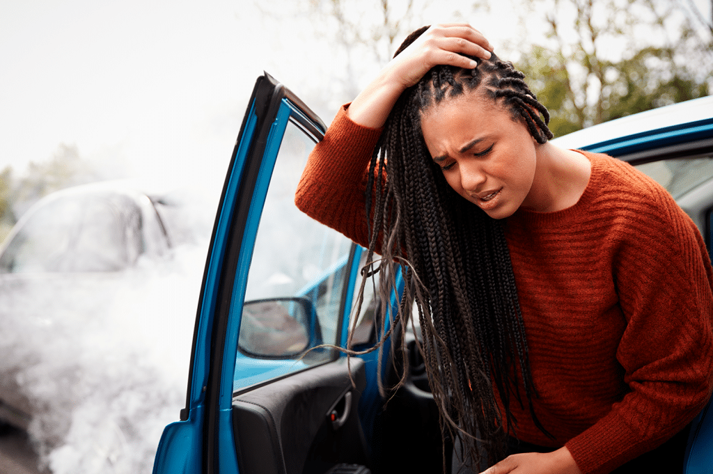 Female motorist with head injury getting out of a car after a crash