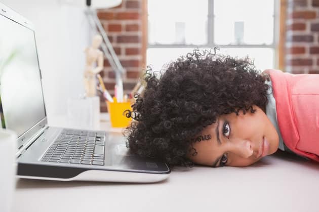 woman with her head on her desk in front of her laptop