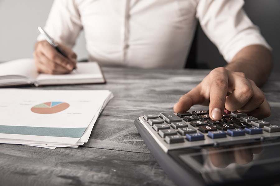 man hand calculator with graph on desk calculating cost of living adjustments