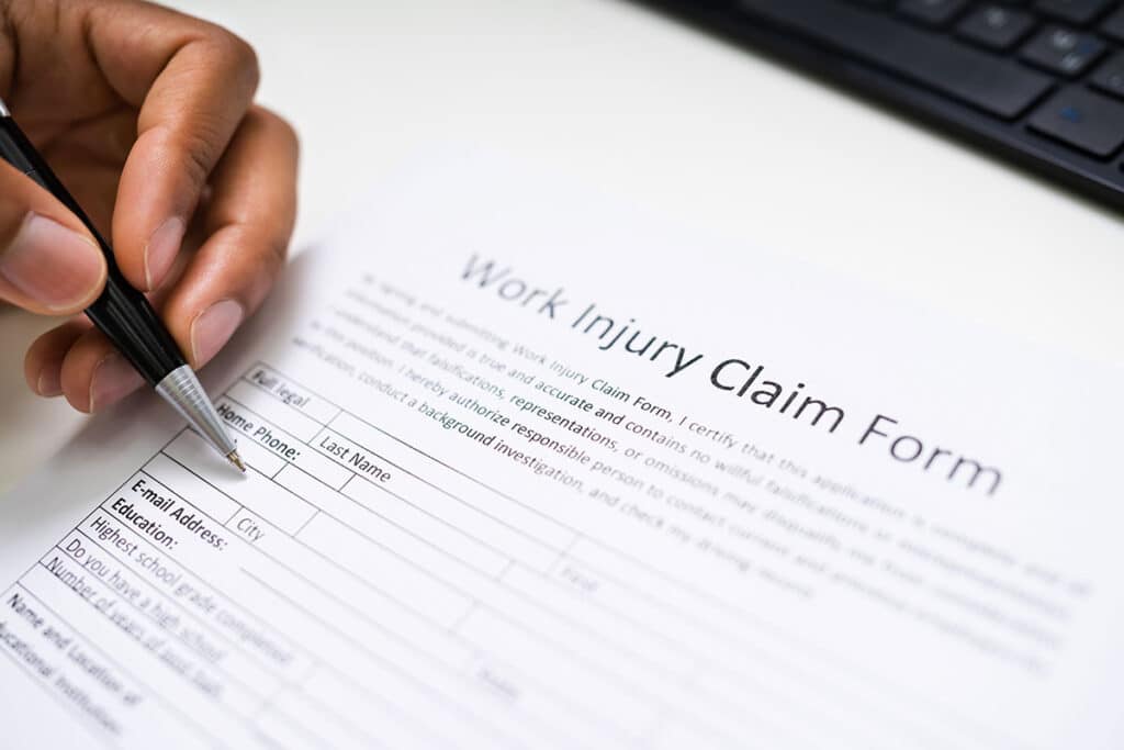 worker filling out work injury claim form with a ball point pen