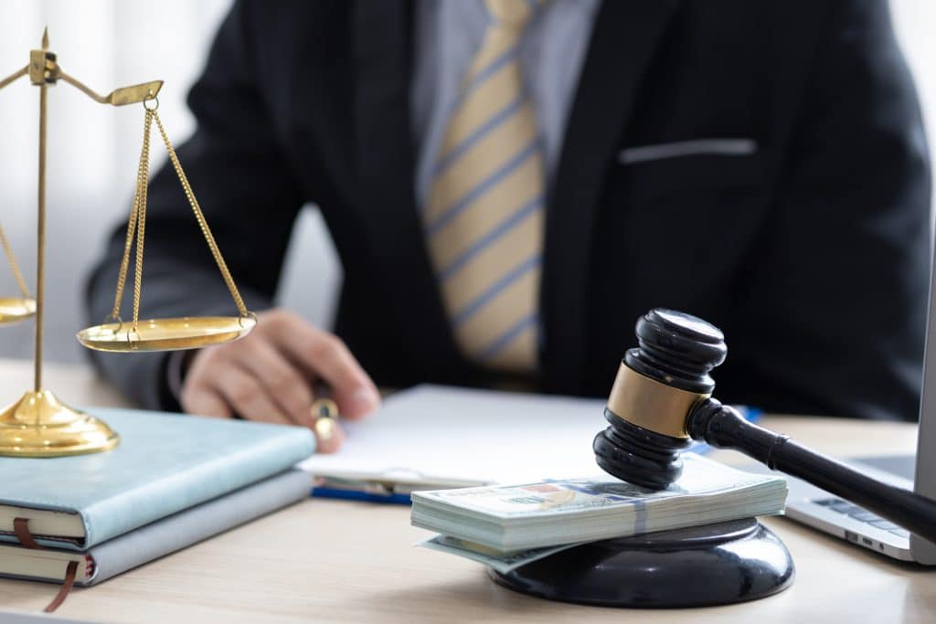 Attorney_with_pen_in_hand_sits_behind_a_gavel_on_a_stack_of_bills