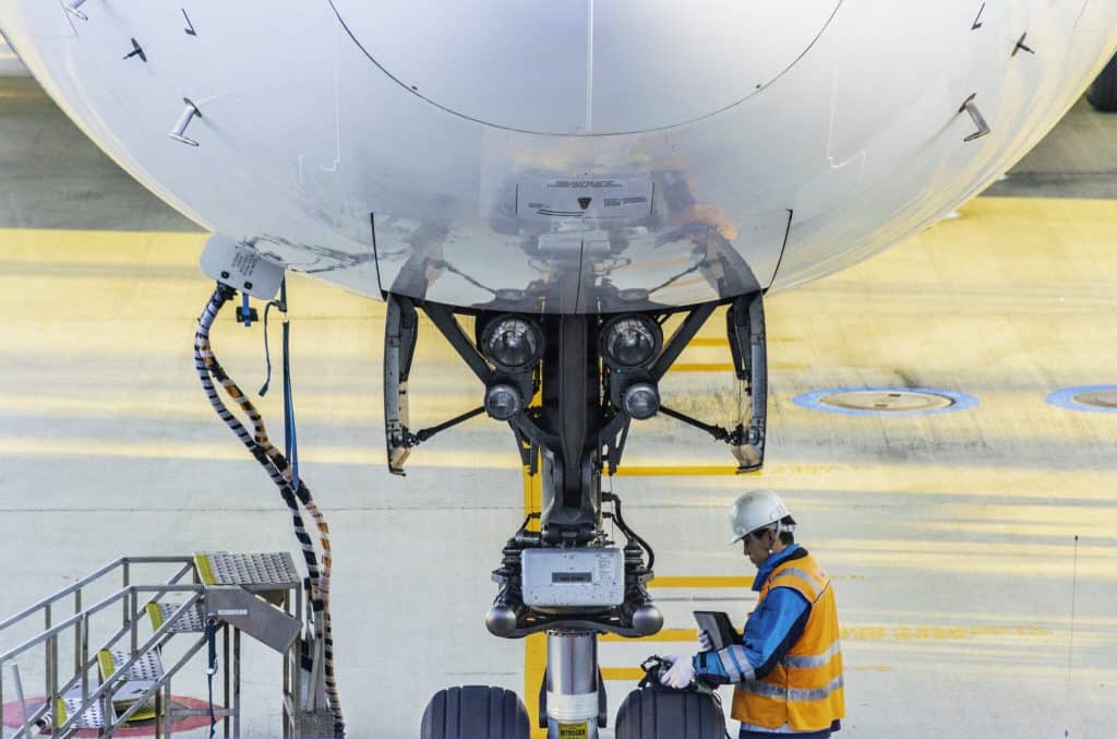 A Boeing Airplane on Ground technician inspects the plane's landing gear.